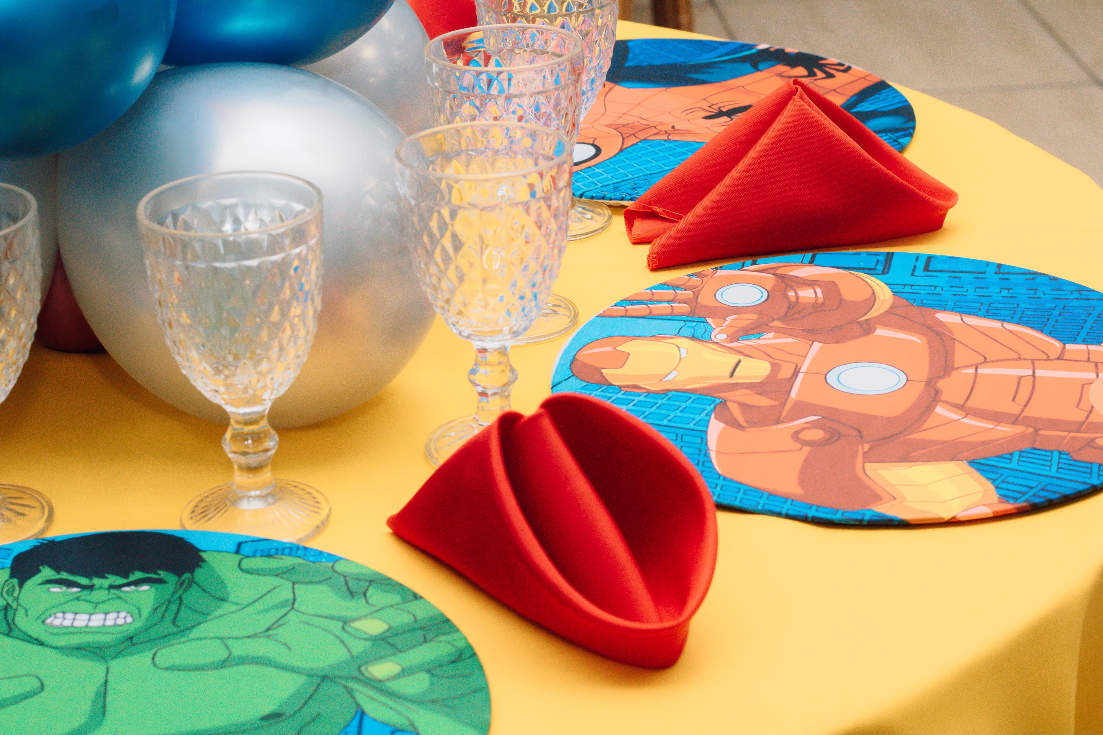 Detalhe dos sousplats temáticos com guardanapos dobrados e taças de cristal